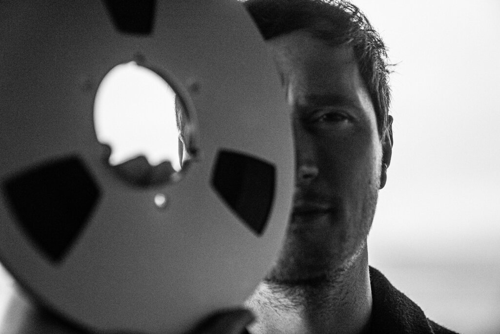 A man holding a reel of film in front of his face.