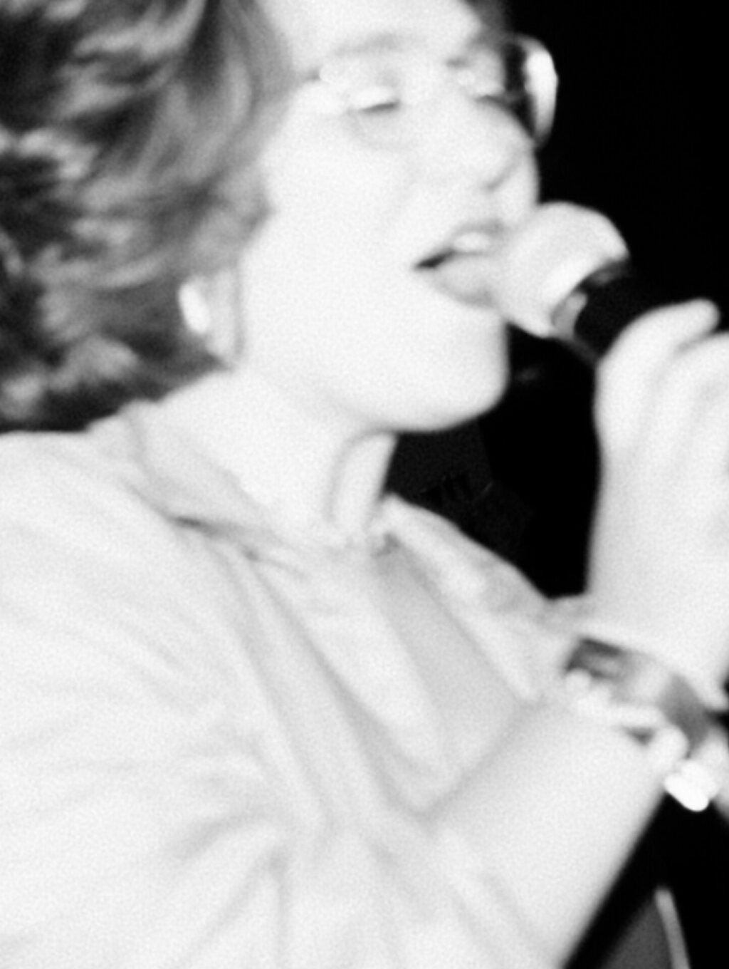 A woman with eyes closed is singing into a microphone.